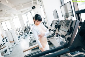 A woman sitting on a stationary bike in a gym.