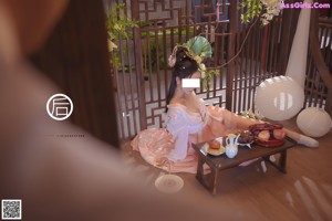 A woman in a pink dress sitting at a table.