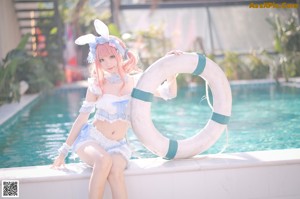 A woman in a bunny costume posing by a pool.