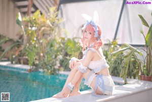 A woman in a bunny costume sitting on the edge of a pool.