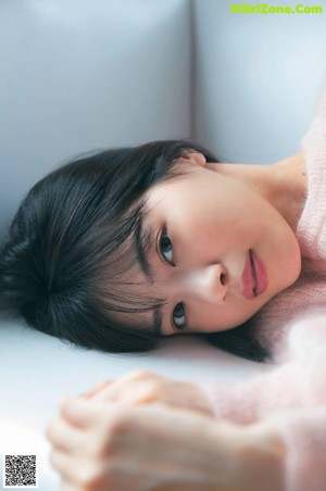 A woman in a pink sweater sitting on a window sill.