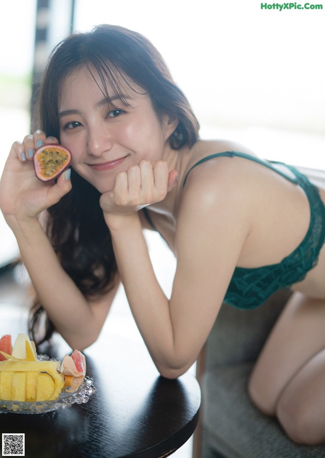 A woman sitting at a table with a plate of fruit.