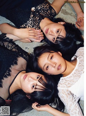 A group of young women sitting on top of a white wall.