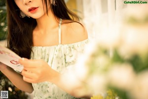 A woman in a green dress holding a magnifying glass.