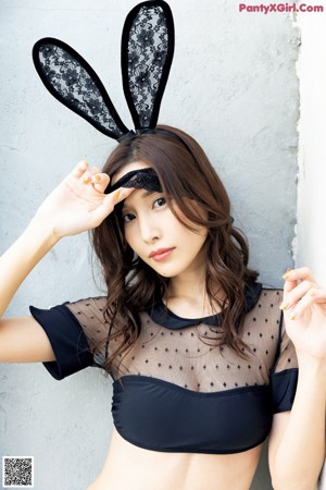 A woman wearing bunny ears and a black top.
