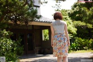 A woman standing on the side of a road next to a fence.