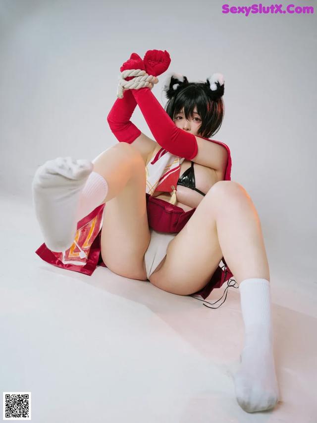 A woman in a red and white outfit is tied up with a rope.