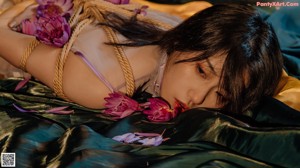A woman tied up with flowers on a rope.