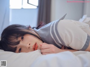 A woman in a school uniform laying on a bed.