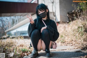 A woman in a skirt and knee high socks is posing for a picture.