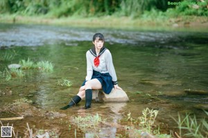 A woman in a school uniform sitting in the water.