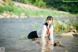 A woman in a sailor outfit is standing in the water.