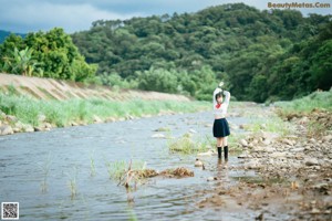 A woman in a school uniform is sitting in the water.