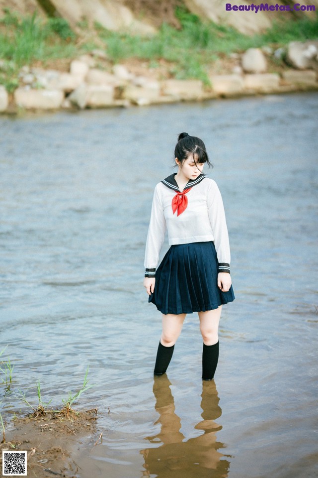 A woman in a sailor outfit standing in the water.