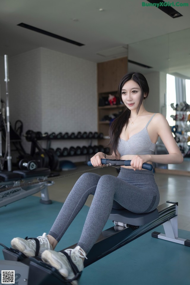 A woman sitting on a rowing machine in a gym.