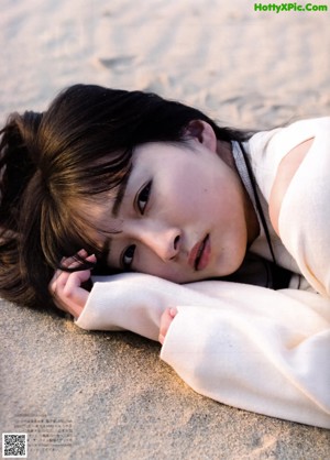 A woman laying on the sand on a beach.
