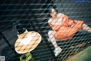 A woman in an orange jumpsuit sitting at a table.