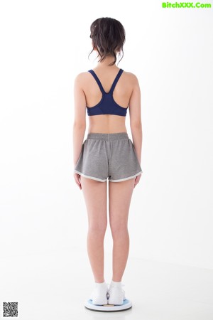 A woman in a sports bra top and shorts posing for a picture.