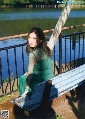 A woman with long brown hair wearing a green dress.