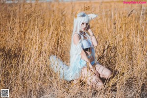 A woman in a white outfit holding a bunch of wheat.