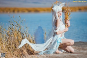 A woman in a white dress holding a bunch of wheat.