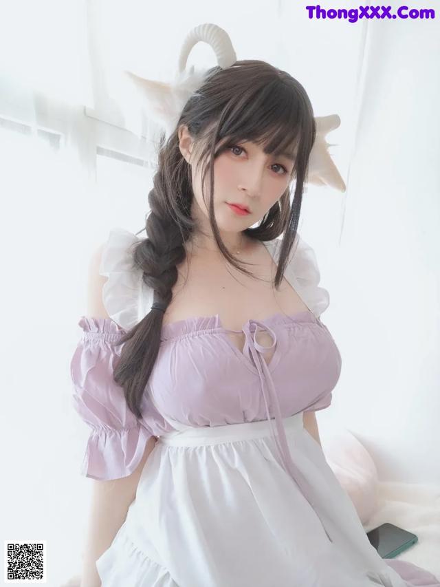a woman in a purple dress sitting on a bed