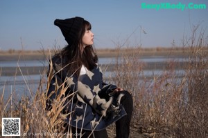 A woman sitting under a tree in the desert.