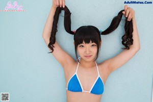 A woman in a blue and white bikini leaning against a wall.