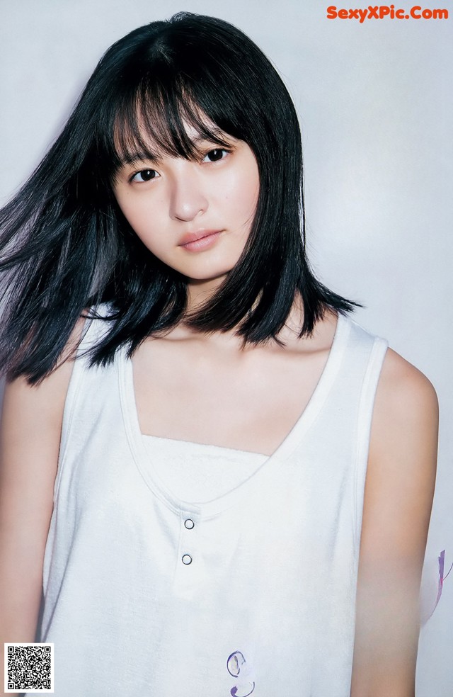 A woman with long black hair wearing a white tank top.
