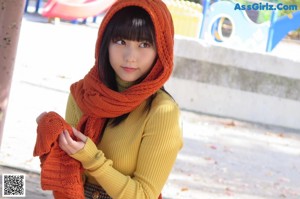 A woman in a yellow sweater is sitting on a red slide.