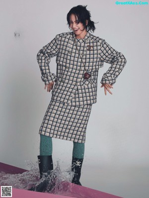 A woman in a blue and brown coat and brown boots.