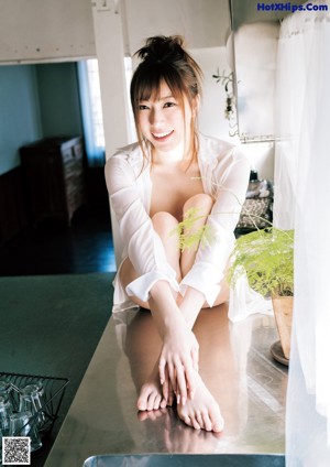 A naked asian woman standing in front of a window.