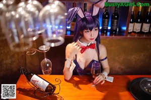 A woman sitting on a stool in front of a bar.