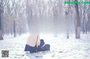 A woman sitting on the ground in the snow.