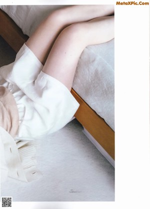 A woman laying on the floor wearing a white cardigan.