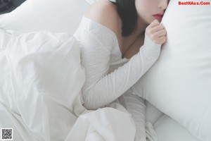 A woman sitting on top of a white bed.