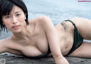 A woman standing on the side of a road next to the ocean.