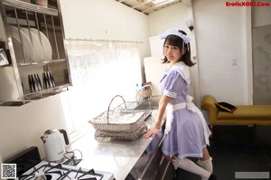 A woman in a maid outfit sitting on a couch.