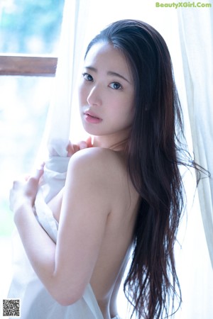 A woman in a white lingerie laying on a bed.