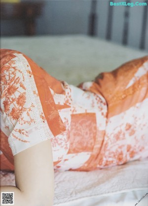 A woman sitting on a bed in a dress.