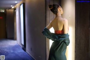 A woman in a green dress standing in a bathroom.