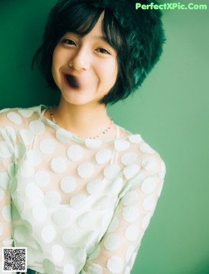 A young woman wearing a white sweater and a green scarf.