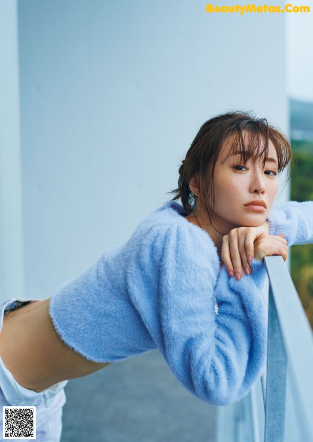 A woman leaning on a railing with her hand on her hip.