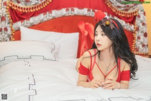 A woman in a red lingerie sitting on a bed.