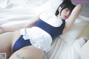 A woman in a blue bodysuit laying on a bed.